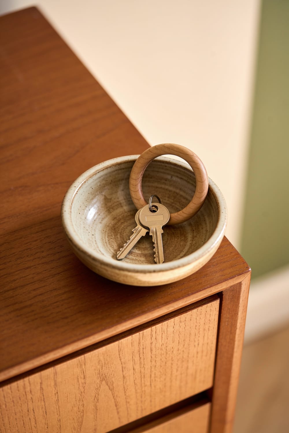 Wohnungsschlüssel in einer Keramikschale auf einem Sideboard.